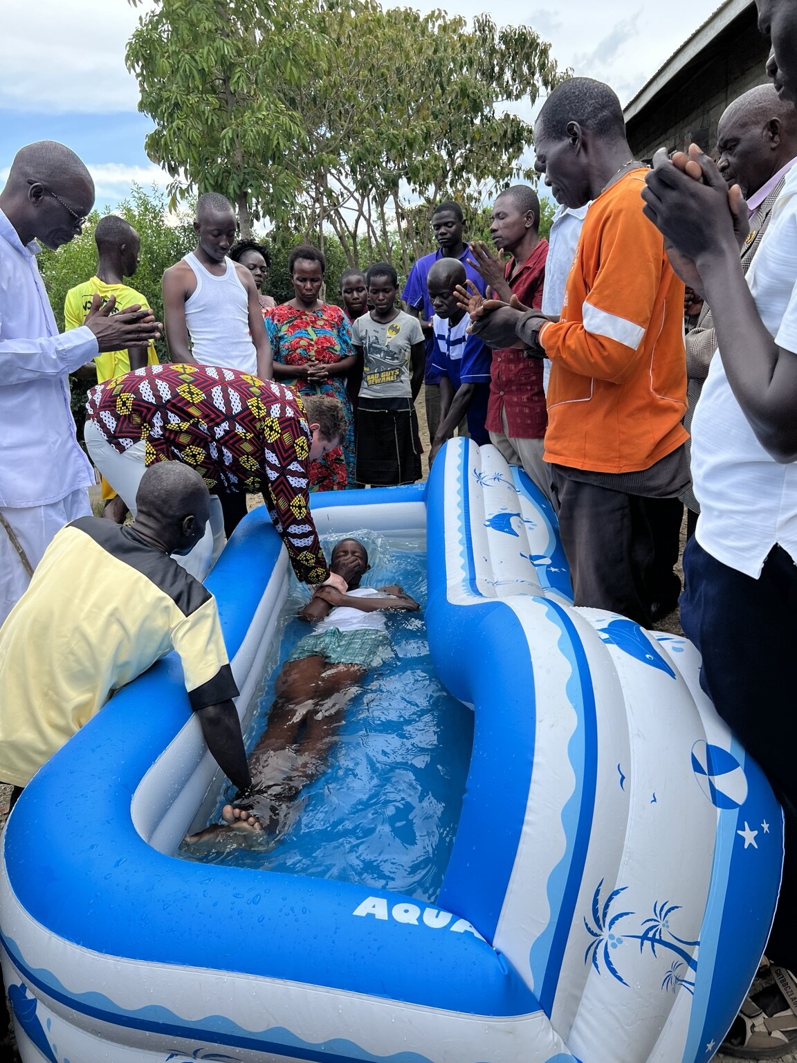 A community gathered in prayer around a baptism