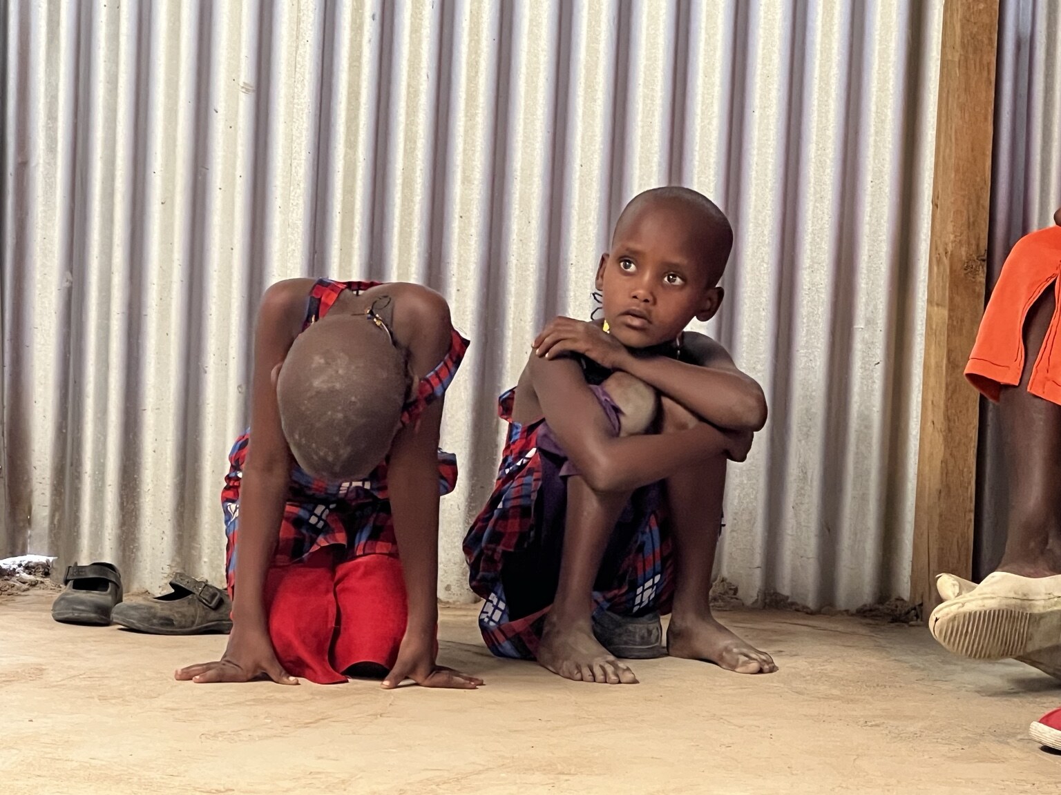 Two children sitting together inside a community building