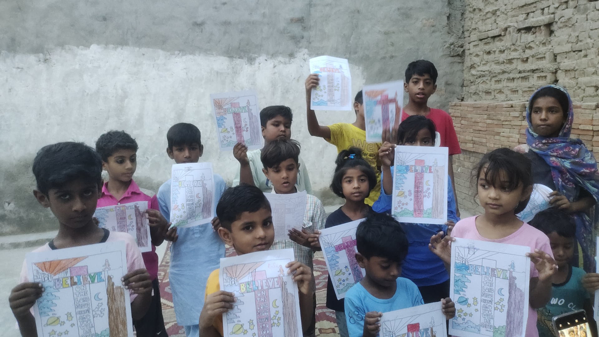 Children holding Bible-themed artwork in Pakistan